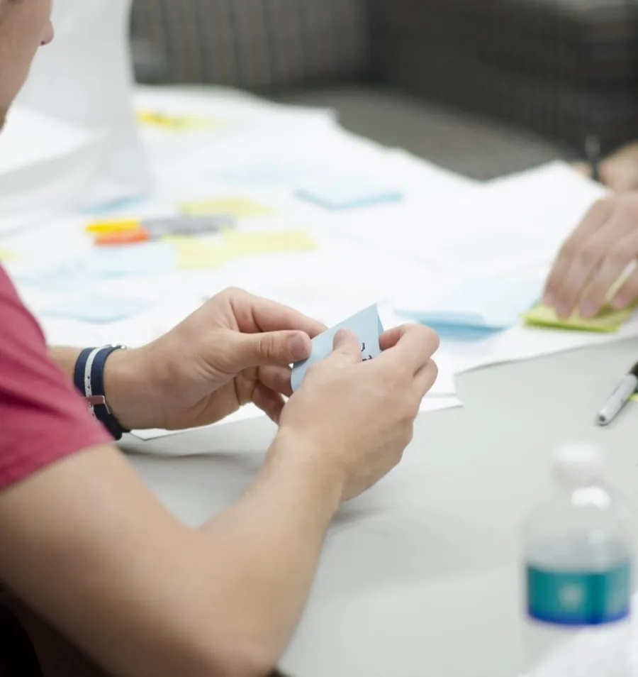 Designers arranging sticky notes and printed layouts across a studio table